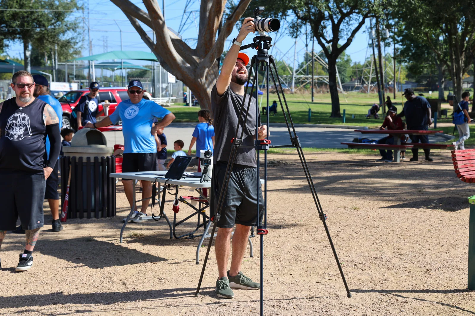 Photographer at the camera with families and teams moving through behind
