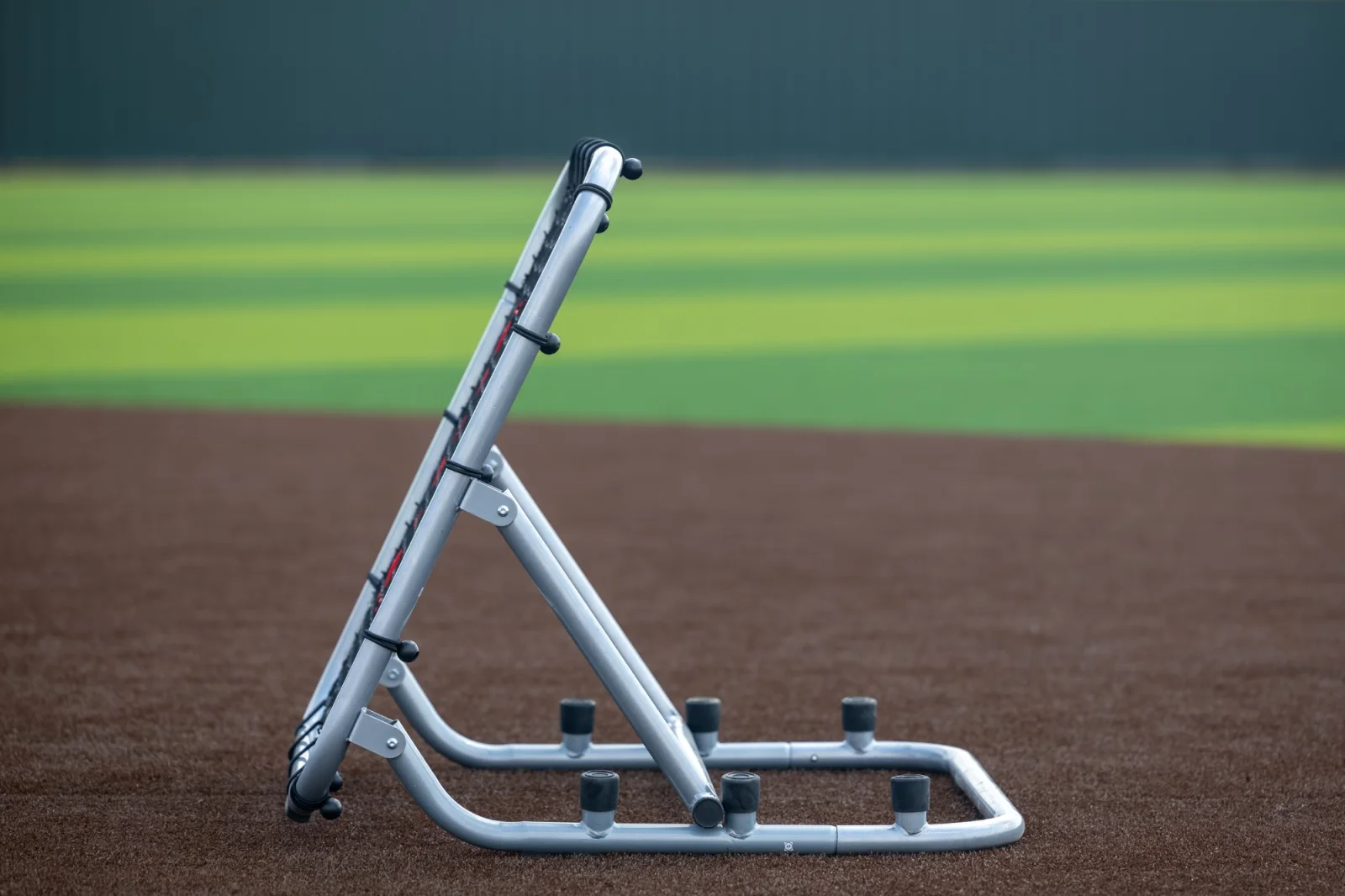 Profile of a rebounder trainer on the infield with the outfield falling into soft focus