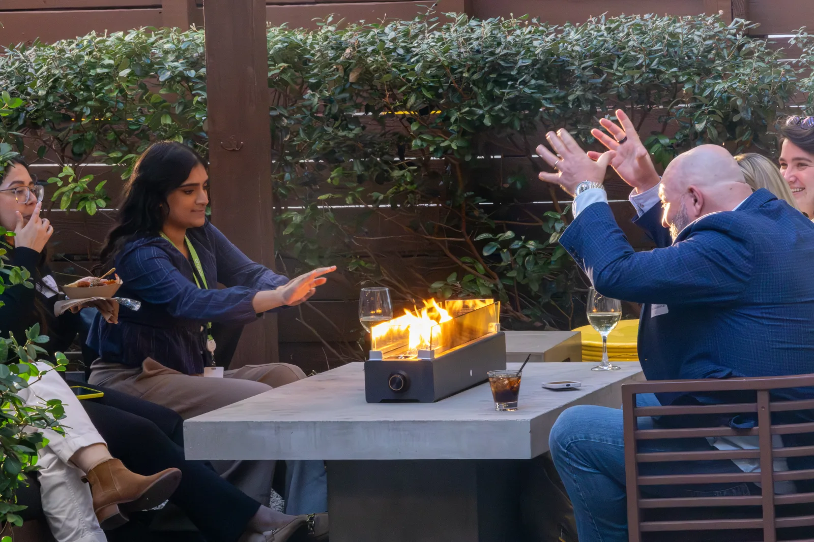 Members seated around a firepit table as the light drops