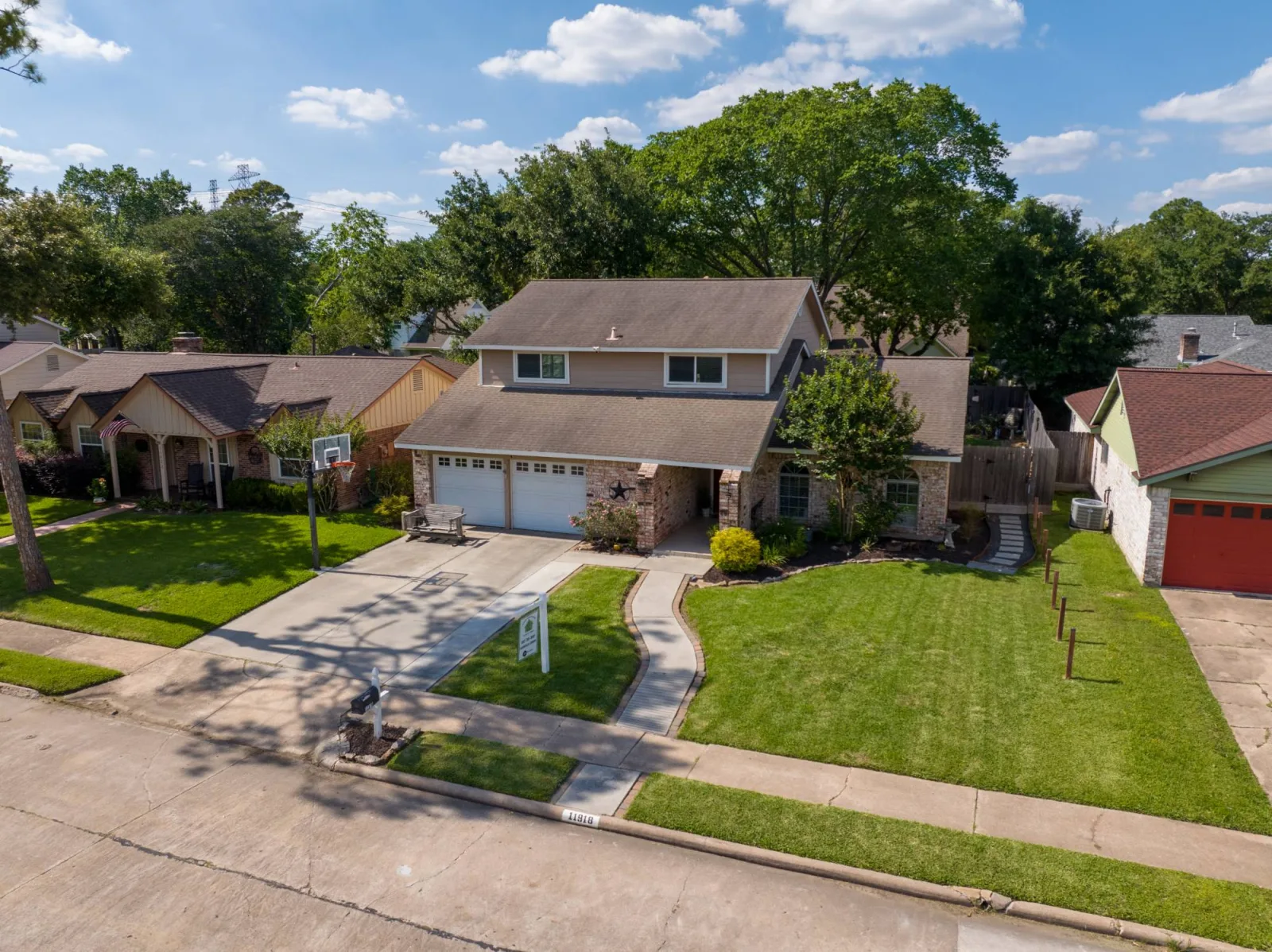 Low aerial frame of a Meadows Place property showing the front approach and neighboring homes