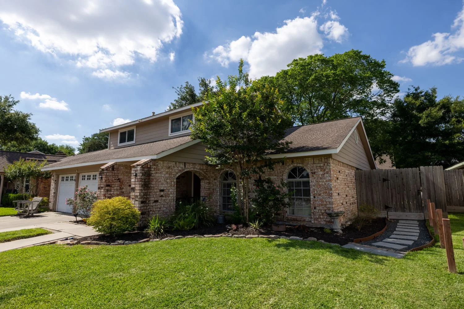 Front elevation of a Meadows Place listing showing brick detail and mature landscaping