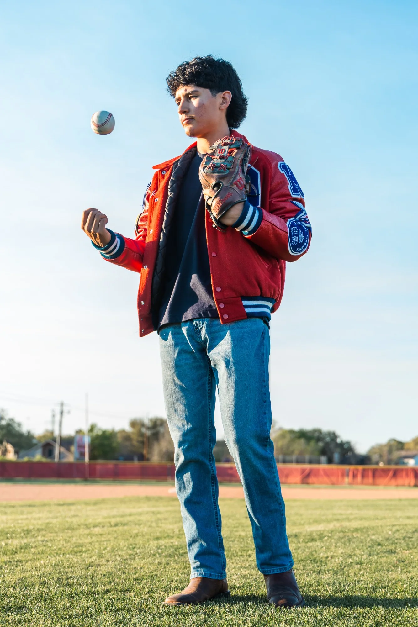 Full length frame of a senior on the outfield grass tossing a ball
