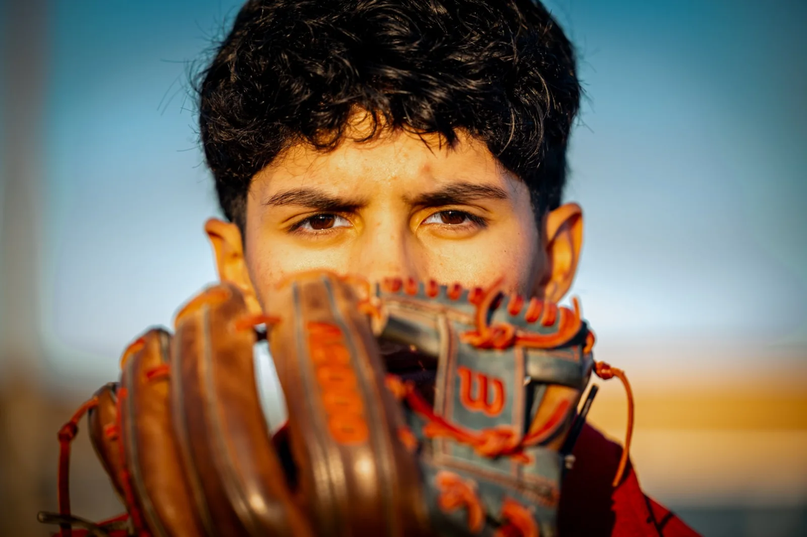 Senior holding his glove beside his face in warm evening light