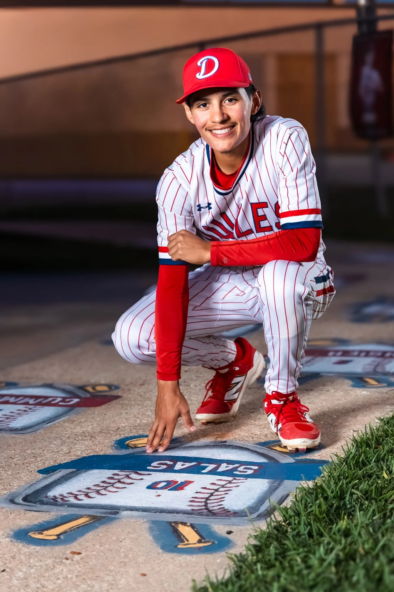 Senior crouched beside a base painted with his name and number