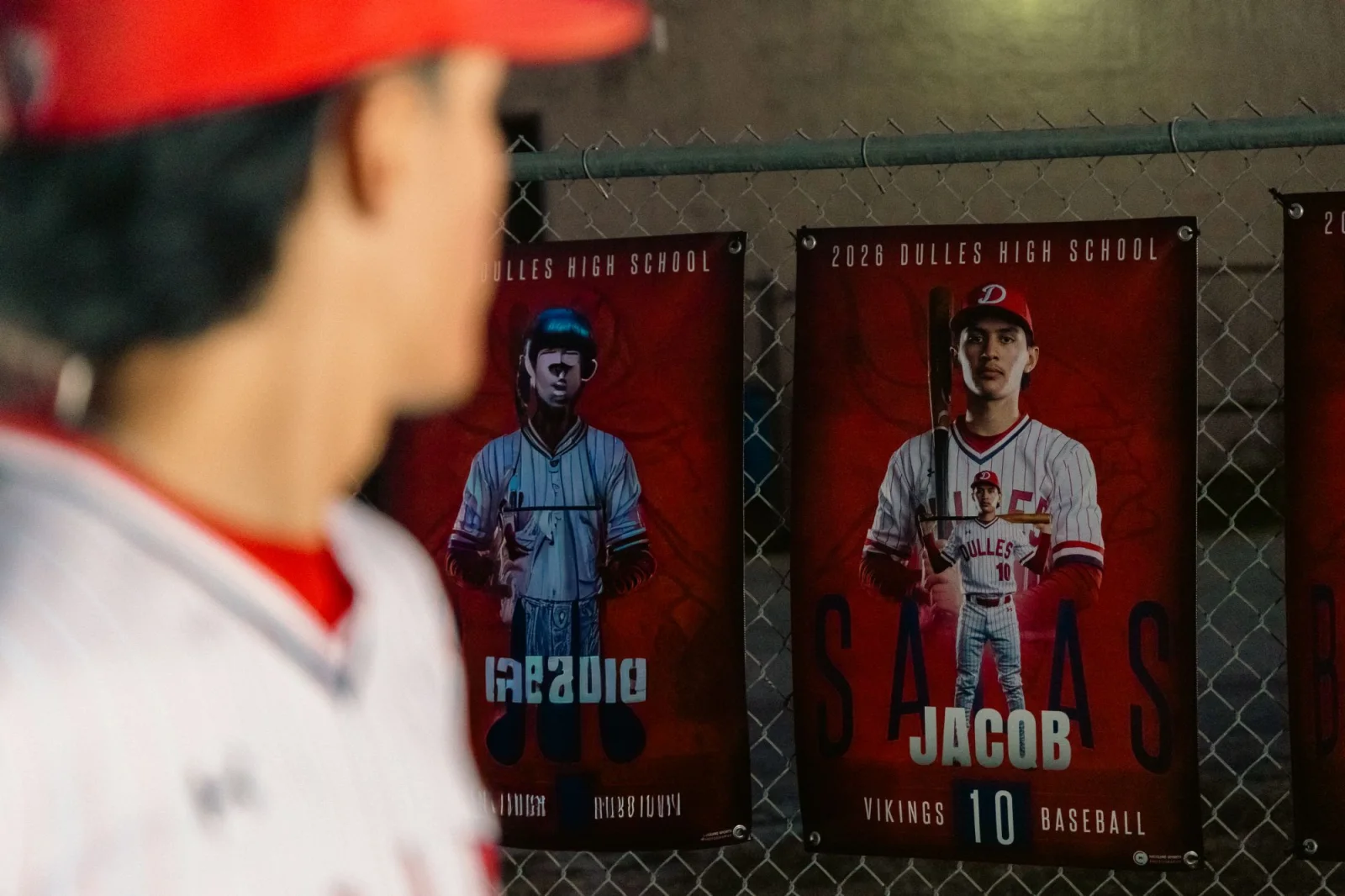 Senior looking at his printed senior banner hanging on the ballpark fence